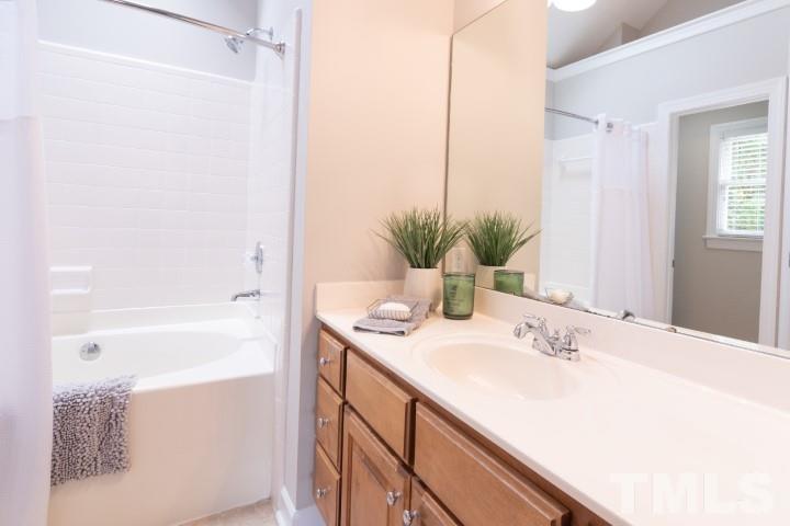 6940 Spring Drive Raleigh, NC 27613 - Photo 14 of 18 a bathroom with a sink a mirror and a bathtub