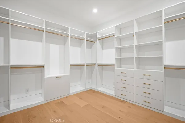 a view of an empty room with wooden floor and a bathroom