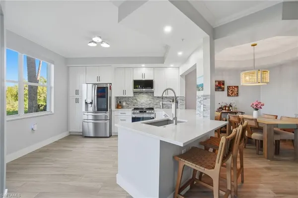 a kitchen with stainless steel appliances a refrigerator a stove a sink a dining table and chairs