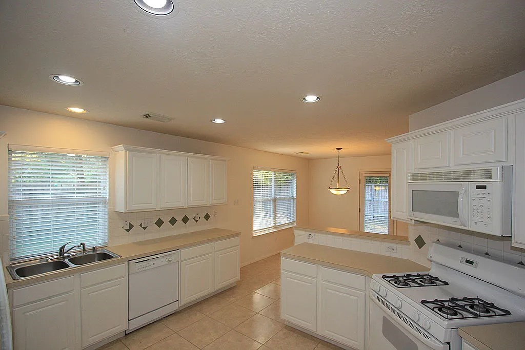 43 Steep Trail Place Conroe, TX 77385 - Photo 6 of 13 a large kitchen with a large counter top space stainless steel appliances and cabinets