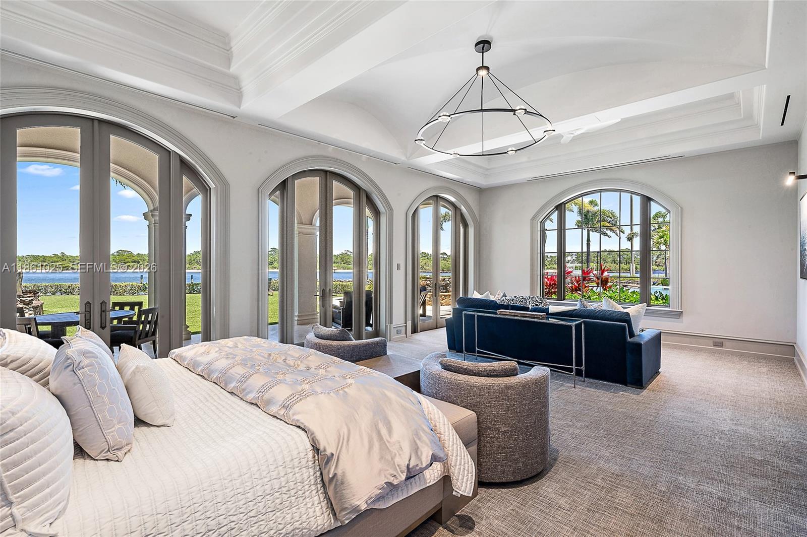 176 Spyglass Lane Jupiter, FL 33477 - Photo 33 of 79 a spacious bedroom with a bed a chandelier and a large window