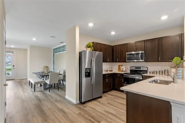 a kitchen with granite countertop a refrigerator a stove a sink a dining table and chairs