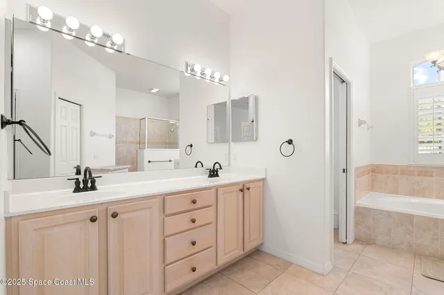 a bathroom with a double vanity sink a large mirror and a bathtub