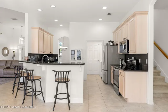 a kitchen with stainless steel appliances a sink a stove a refrigerator cabinets and a dining table