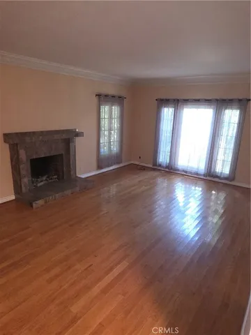 an empty room with wooden floor fireplace and windows