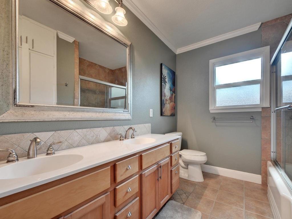 610 West N Loop Boulevard Austin, TX 78751 - Photo 18 of 29 Bathroom featuring a double vanity with light wood cabinetry, dual sinks, and a large framed mirror