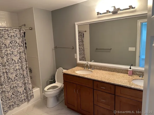 a bathroom with a granite countertop sink toilet and mirror