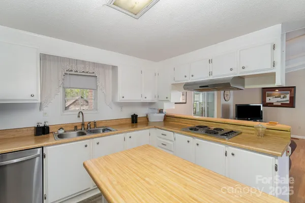 a kitchen with stainless steel appliances a stove a sink and white cabinets