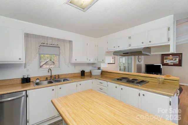 a kitchen with stainless steel appliances a stove a sink and white cabinets