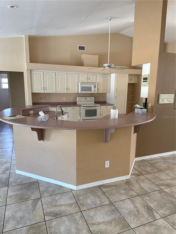 29310 Bryan Way Punta Gorda, FL 33982 - Photo 9 of 30 a kitchen with kitchen island granite countertop a sink a counter top space cabinets and stainless steel appliances