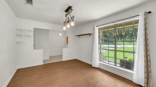 a view of empty room with wooden floor and fan