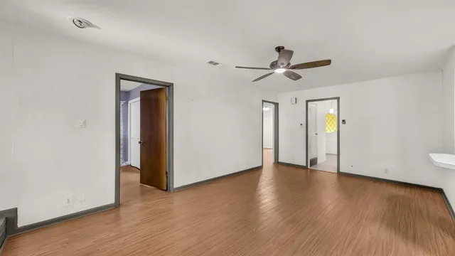 a view of an empty room with a window and wooden floor