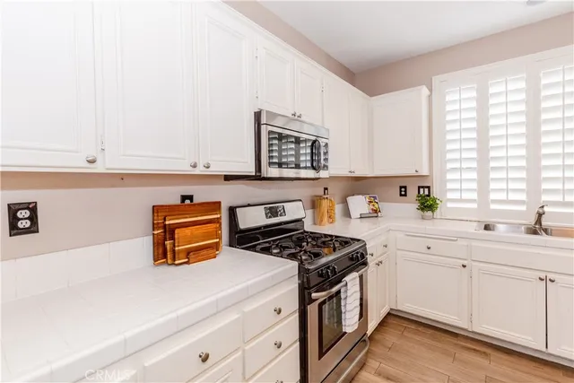 a kitchen with stainless steel appliances a stove a sink and white cabinets