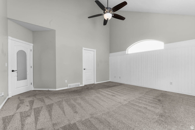 1417 Blacksmith Lane Draper, UT 84020 - Photo 22 of 57 Vaulted ceiling room featuring light gray walls, a ceiling fan with integrated lighting, and a prominent arched window above white beadboard paneling