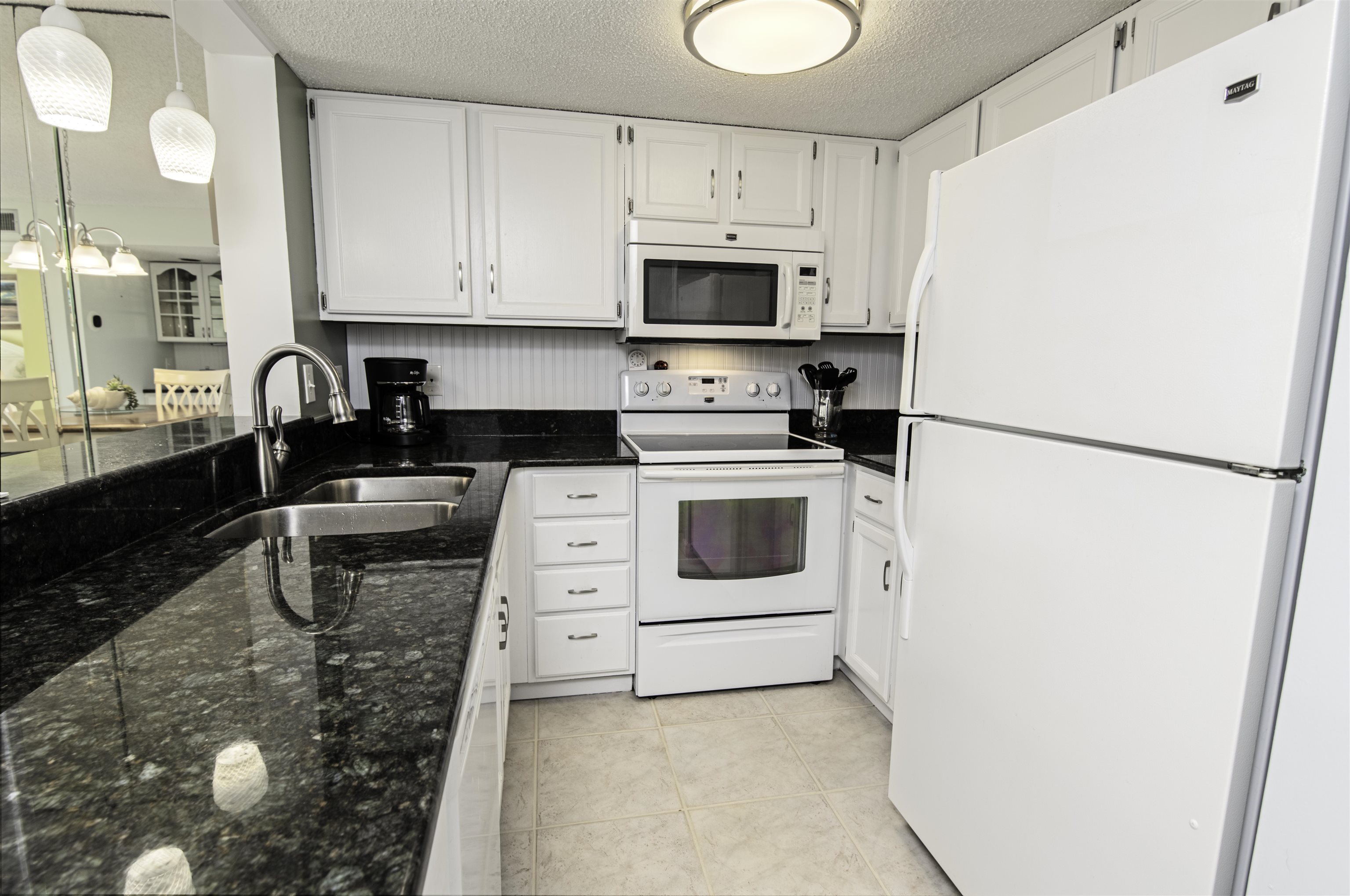 880 A1A Beach Boulevard, Unit 7302 St. Augustine, FL 32080 - Photo 6 of 28 a kitchen with a refrigerator a stove a microwave and cabinets