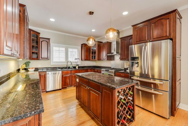 a kitchen with stainless steel appliances granite countertop a sink a stove and a refrigerator
