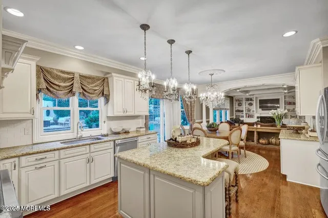 a kitchen with stainless steel appliances granite countertop a sink and a wooden floor