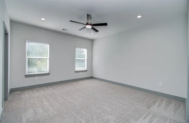 an empty room with windows and fan
