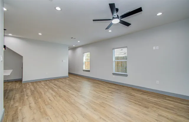 a view of an empty room with a window and a kitchen