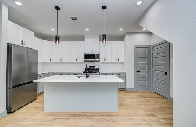 a large kitchen with kitchen island a large counter top stainless steel appliances and cabinets