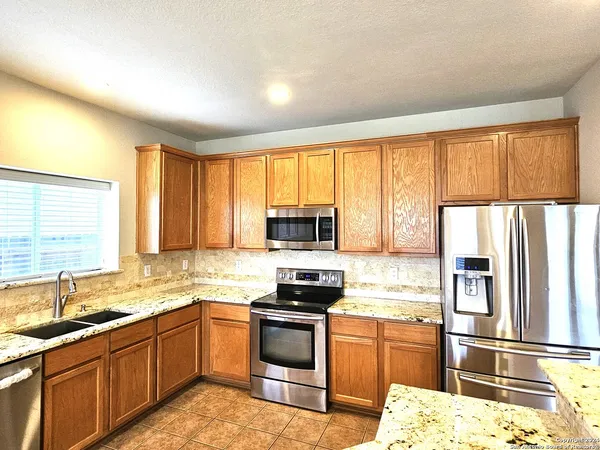 a kitchen with granite countertop a refrigerator stove top oven and sink