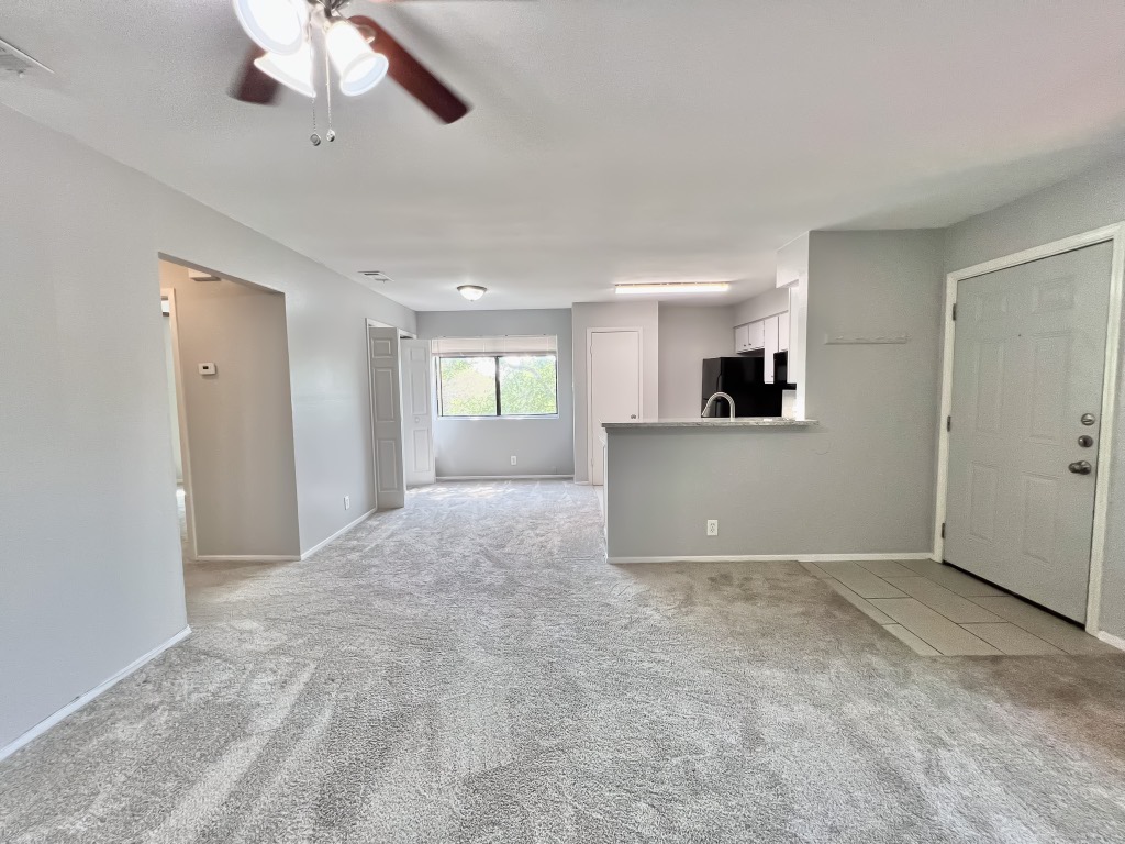 9703 Roxanna Drive, Unit D Austin, TX 78748 - Photo 16 of 24 Unfurnished living room with ceiling fan and light colored carpet