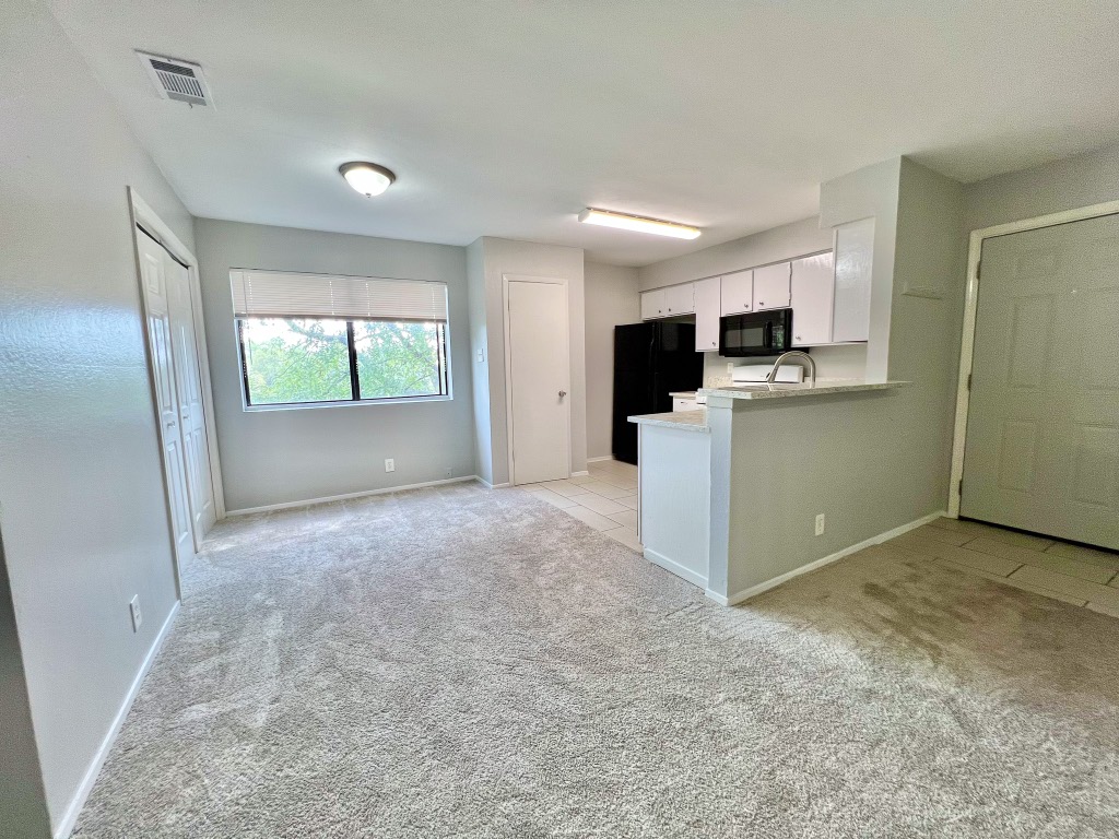 9703 Roxanna Drive, Unit D Austin, TX 78748 - Photo 17 of 24 Kitchen featuring white cabinetry, light carpet, light tile patterned floors, light granite countertops, and black appliances