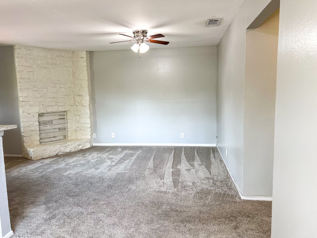 9703 Roxanna Drive, Unit D Austin, TX 78748 - Photo 23 of 24 Unfurnished living room featuring carpet, a stone decorative fireplace, and ceiling fan