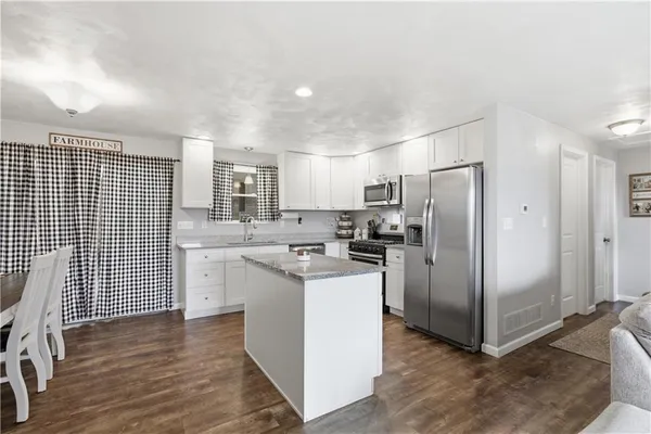 a kitchen with stainless steel appliances granite countertop a refrigerator a stove a sink and white cabinets