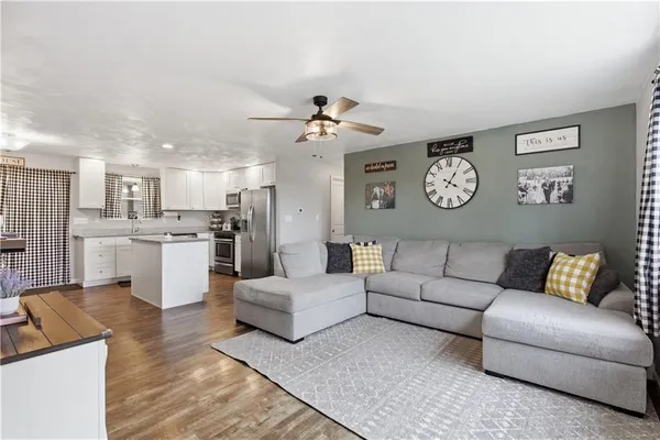 a living room with furniture kitchen view and a chandelier
