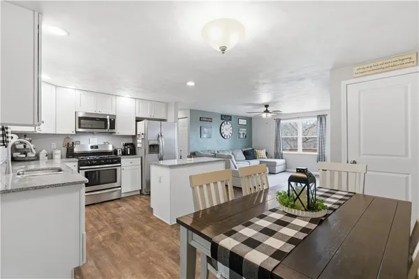a living room with stainless steel appliances furniture a rug and a kitchen view