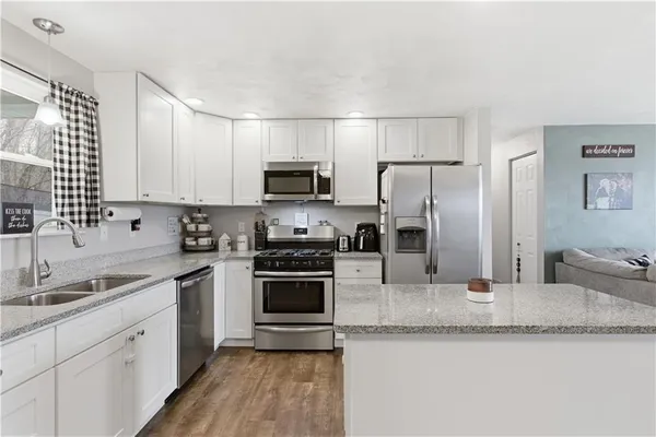 a kitchen with granite countertop a sink stainless steel appliances and white cabinets