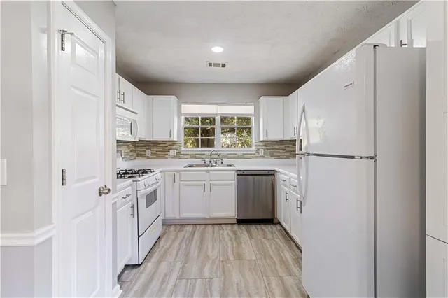 a kitchen with granite countertop appliances a sink and a refrigerator