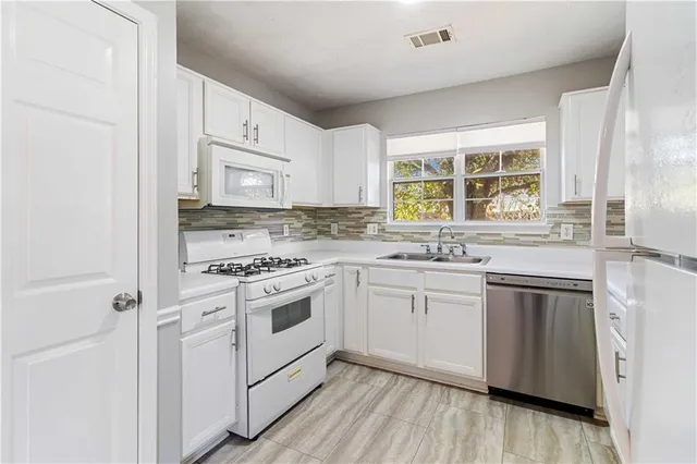 a kitchen with granite countertop white cabinets and white appliances