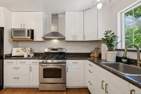a kitchen with stainless steel appliances granite countertop white cabinets granite counter tops and a wooden floors