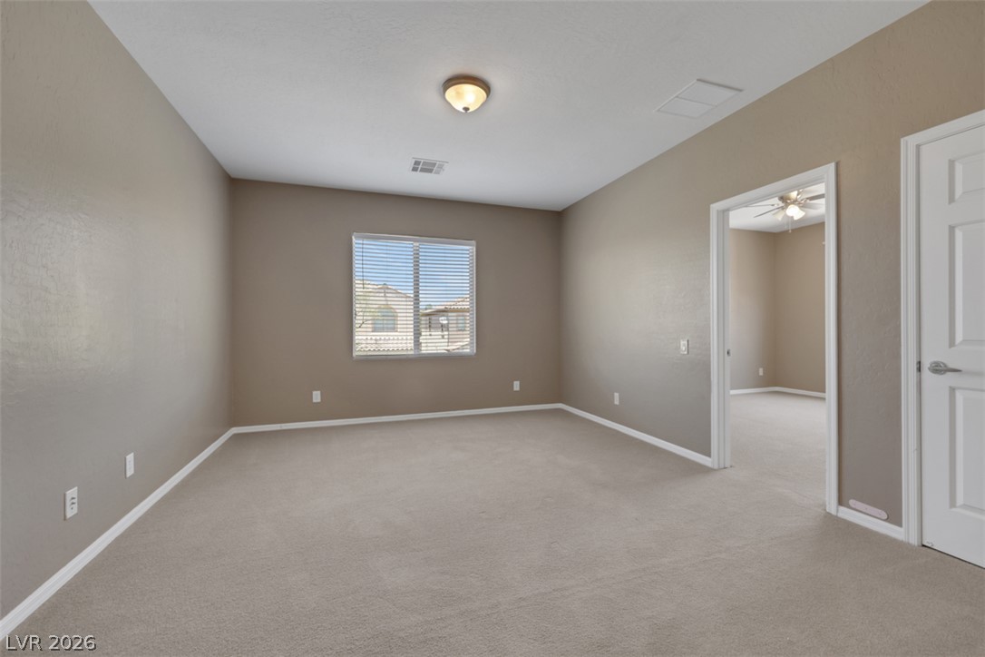 2501 Bechamel Place Henderson, NV 89044 - Photo 22 of 50 A spacious room offers comfortable carpeted flooring and ample natural light from a well-placed window.