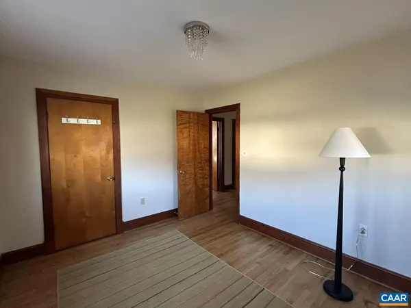 a view of an empty room with wooden floor and closet