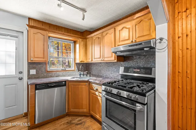 a kitchen with stainless steel appliances granite countertop a stove a sink and a microwave