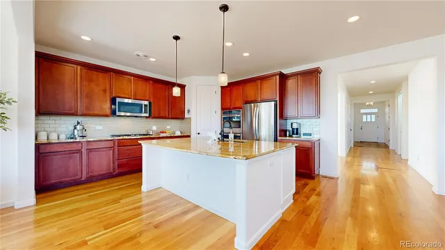 a large kitchen with stainless steel appliances granite countertop a stove and a wooden floors