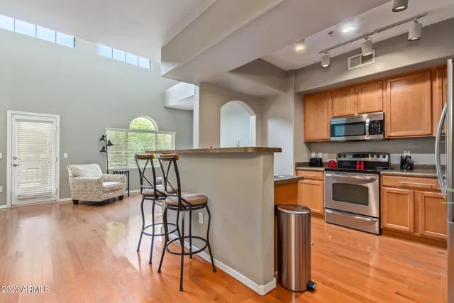 a kitchen with stainless steel appliances a stove a sink dishwasher a microwave oven and a dining table with wooden floor