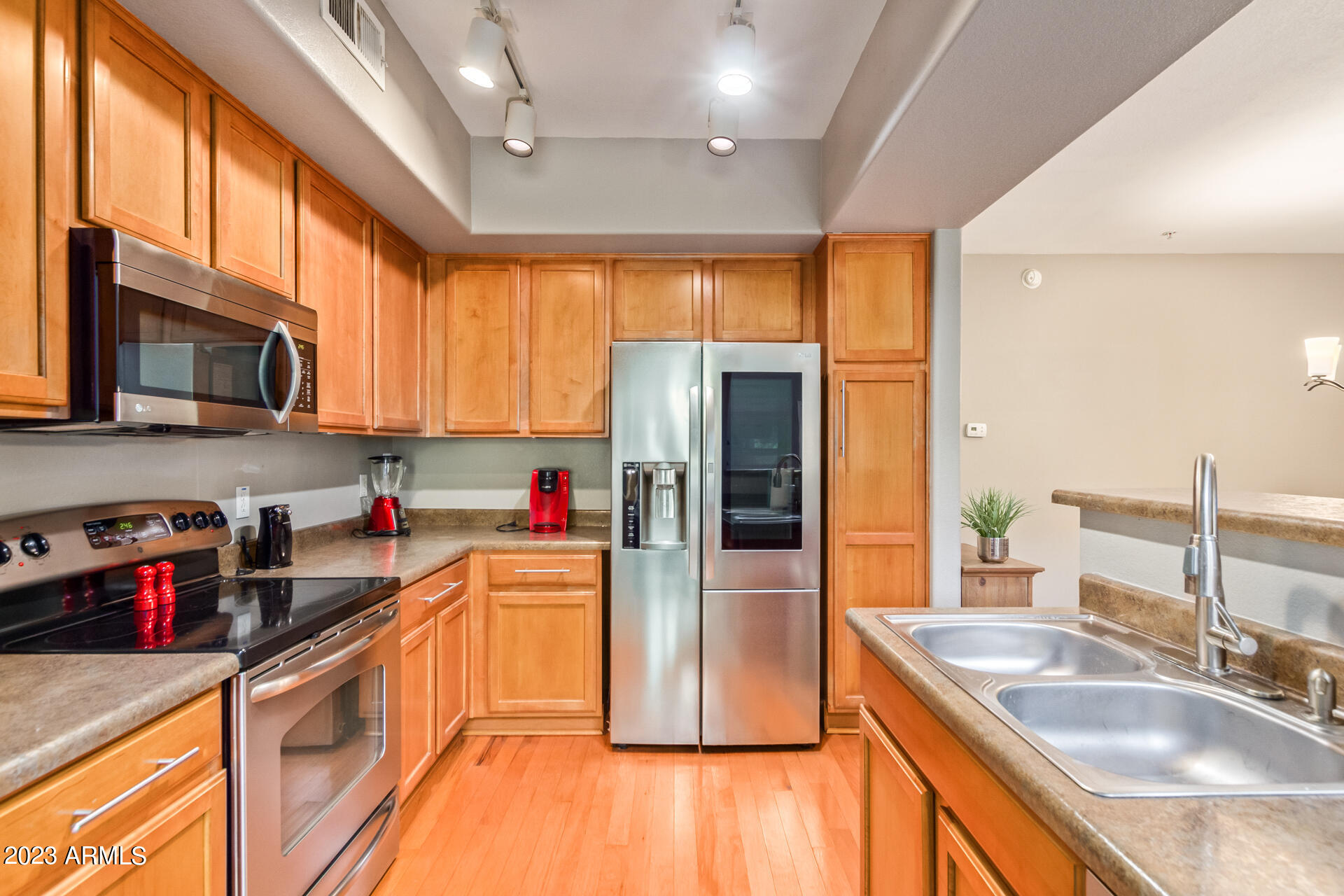 2150 West Alameda Road, Unit 1381 Phoenix, AZ 85085 - Photo 6 of 23 a kitchen with stainless steel appliances granite countertop a refrigerator a sink dishwasher a stove with wooden cabinets and floor