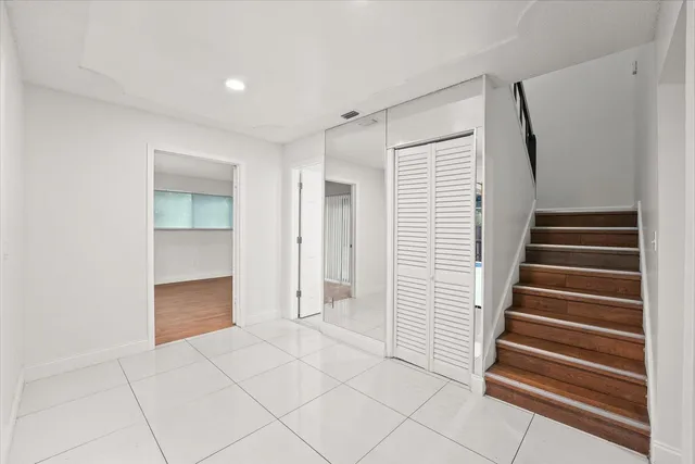 a view of an empty room with wooden staircase and cabinet
