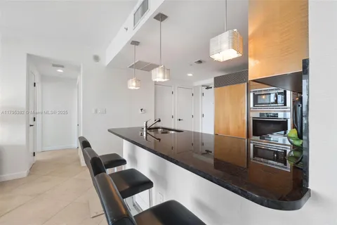 a large kitchen with stainless steel appliances kitchen island granite countertop a sink and chairs
