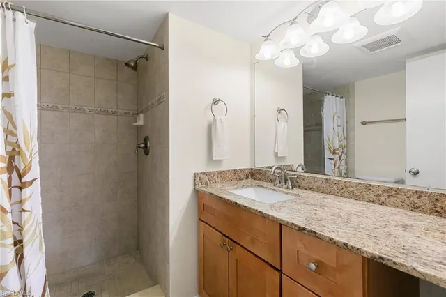 a bathroom with a granite countertop sink a mirror and shower