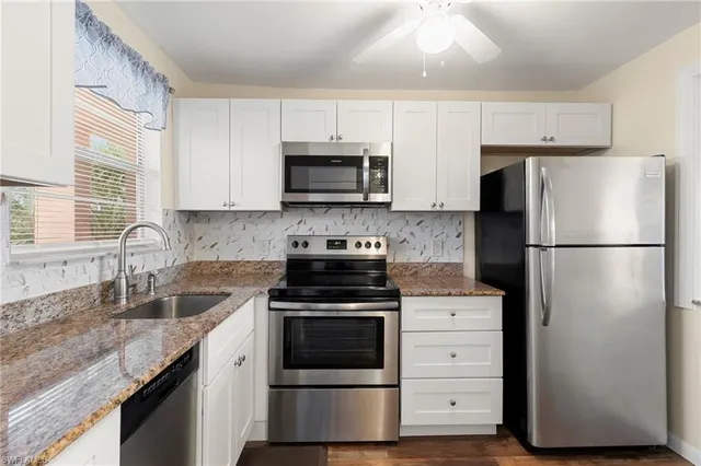 a kitchen with cabinets stainless steel appliances a sink and a window
