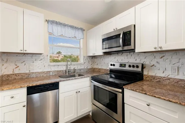 a kitchen with stainless steel appliances granite countertop white cabinets granite counter tops and a stove
