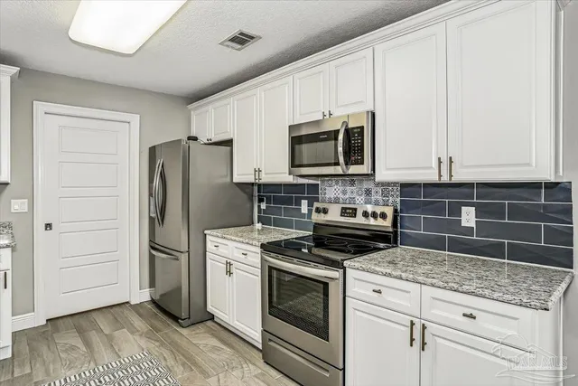 a kitchen with granite countertop a refrigerator stove and microwave