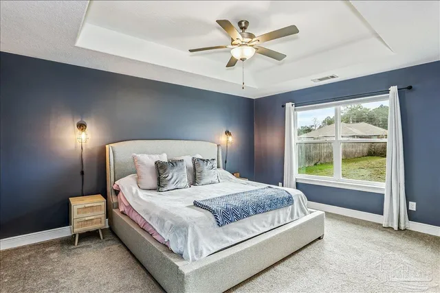 a bedroom with a large bed and a chandelier fan