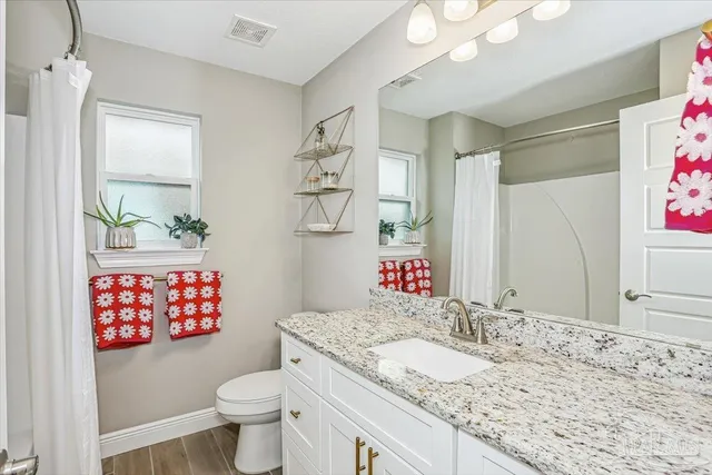 a bathroom with a granite countertop sink mirror vanity and toilet