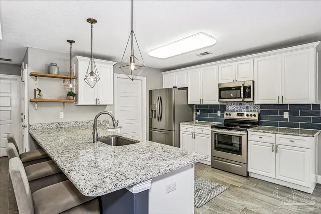 a kitchen with stainless steel appliances granite countertop a sink a stove and a refrigerator